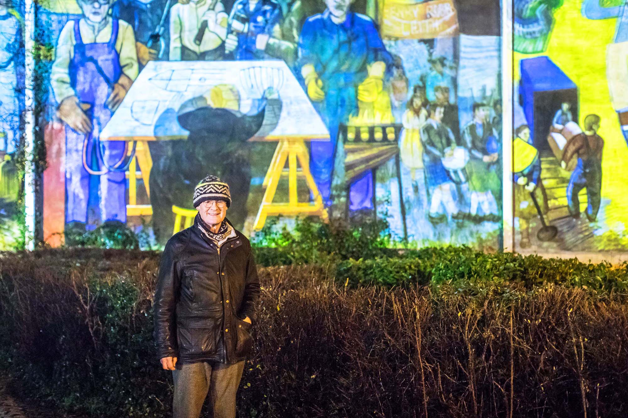man standing in front of leith mural projection